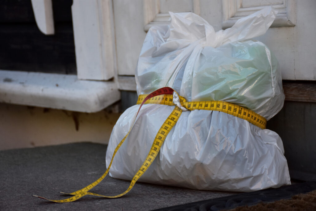 en plastpose med søppel med et knytt målebånd rundt